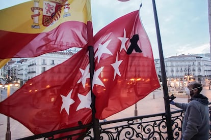 Un trabajador coloca las banderas a media asta en la sede de la Comunidad de Madrid.