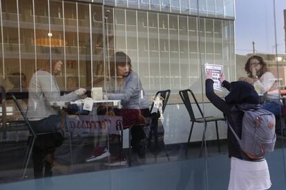 Unas mujeres miran a una chica colocar un cartel en una cafetería de Terrassa.