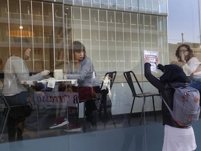 Unas mujeres miran a una chica colocar un cartel en una cafetería de Terrassa.