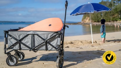 Un carrito en la playa con un bebe debajo de una sombrilla de fondo