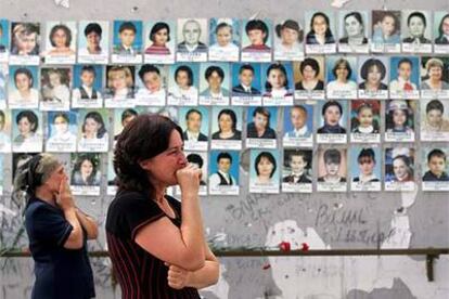 Dos mujeres expresan su dolor ante un muro con fotografías de las víctimas de la masacre ayer en la escuela de Beslán.