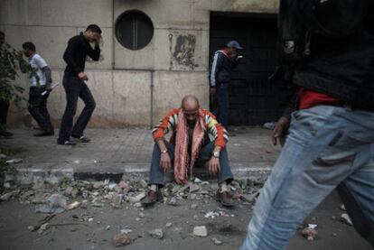 Un manifestante se recupera tras recibir un impacto de gas lacrimógeno durante los enfrentamientos de ayer en El Cairo.