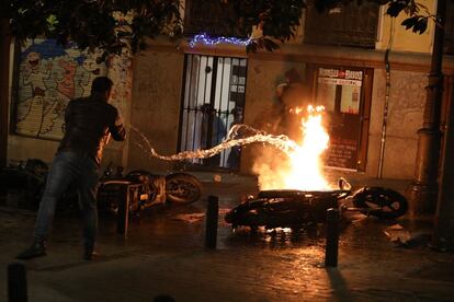 Vecinos de Lavapiés apagando varias motos incendiadas durante las protestas.