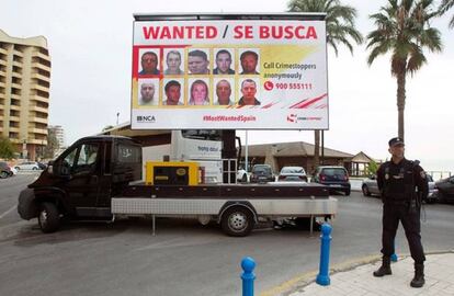 Un policía delante de una de las vallas en las que se exhiben las caras de los delincuentes más buscados de la Costa del Sol. 