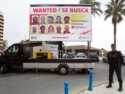 Un policía delante de una de las vallas en las que se exhiben las caras de los delincuentes más buscados de la Costa del Sol. 