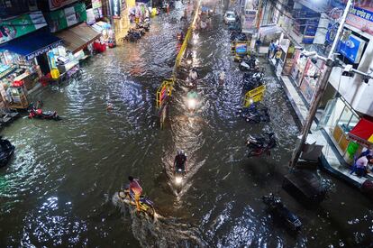 Motoristas transitan a través de una calle inundada después de las fuertes lluvias en Allahabad (India).