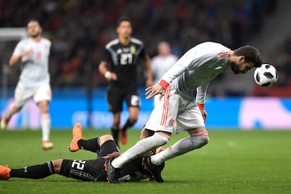 El defensor de la selección española Gerard Piqué trata de llevarse un balón de cabeza en un choque con el jugador argentino Lautaro Martínez. 
