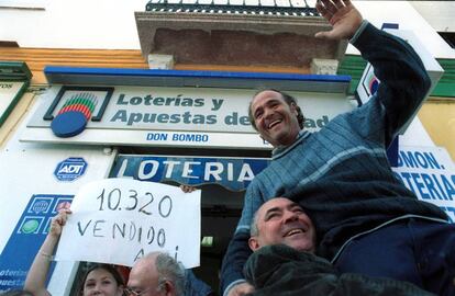 Los afortunados con el primer premio del sorteo de El Niño de la barriada del Puerto de la Torre, en Málaga, celebran su suerte ante la administración que lo vendió.