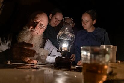 Henrique Loewen, a la luz de una vela, junto a sus hijas, observa la foto de un viejo amigo suyo, Isaac Peter, quien padece un fatal melanoma.