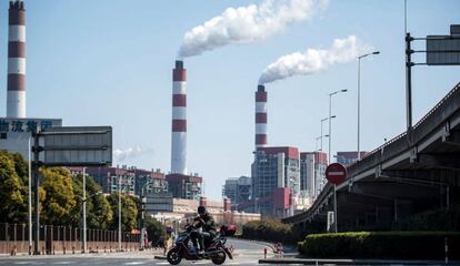 Um motociclista passa em frente a chaminés de uma central de geração elétrica em Xangai (China).