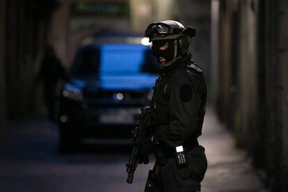 Un agente del Grup Especial d Intervencio (GEI) custodia uno de los pisos en la calle Santa Margarido.