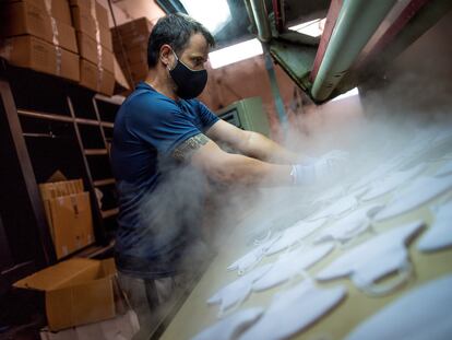 Un trabajador fabrica mascarillas de tela reutilizables en una empresa de Sonseca (Toledo).