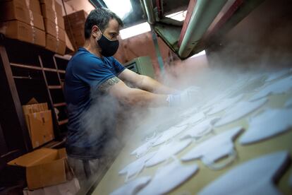 Un trabajador fabrica mascarillas de tela reutilizables en una empresa de Sonseca (Toledo).