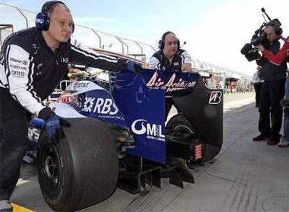 Dos mecánicos de la escudería Williams empujan uno de los coches del equipo, que utiliza los difusores que son objeto de controversia.