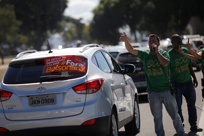 Apoidores de Bolsonaro se manifestam ao lado de carro com faixa contra o presidente, próximo ao Congresso Nacional, em Brasília, em 13 de junho.