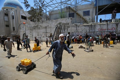 Varios grupos de palestinos recolectan agua debido a la falta de suministros, este lunes en Jan Yunis, al sur de la Franja.