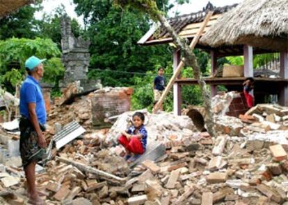 Una familia observa los restos de su casa en Bali, destrozada por el seísmo.