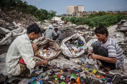 Los recicladores hacen grupos para repartirse el trabajo. La separación de los restos que puedan contener metal de los que no, es la primera de sus misiones. Al fondo, un hospital observa de lejos la realidad de la orilla del río.