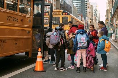 Niños migrantes toman un autobús escolar, vigilados por sus tutores, frente al Hotel Row de Nueva York, que sirve de albergue para migrantes, en diciembre de 2023.