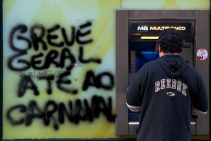 Un cliente usa un cajero en Lisboa, junto a la pintada de una huelga, el pasado noviembre.