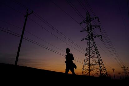 A jogger passes power lines during a sunset run, Aug. 20, 2023, in San Antonio, as high temperatures continue to stress the power grid.