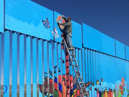 Un artista interviene el muro fronterizo entre México y Estados Unidos en San Diego, California.