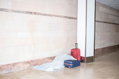 Una persona duerme en los pasillos que conectan la terminal 1 y 2 de Barajas durante la madrugada del lunes. 