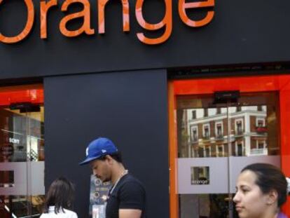 Paseantes delante de un establecimiento de Orange en Madrid.