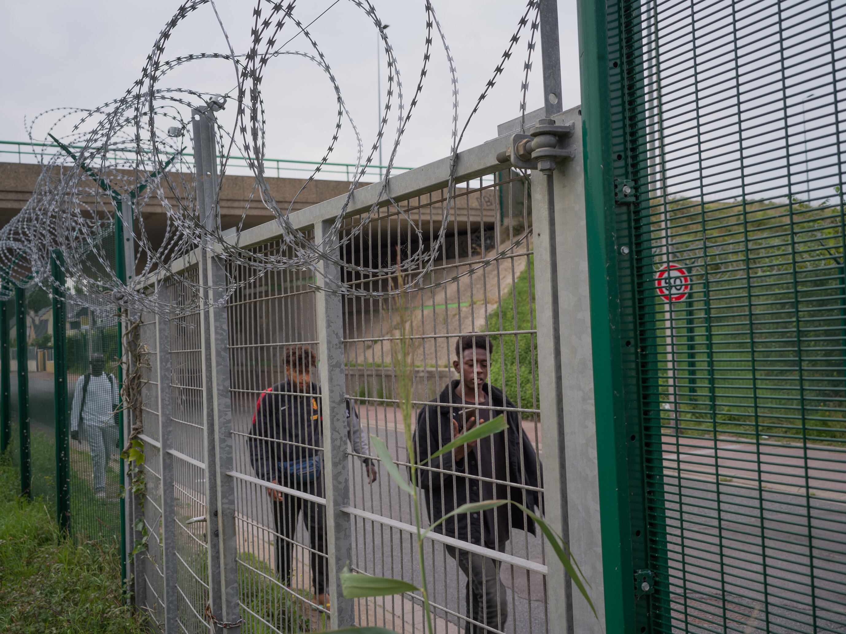 Un grupo de inmigrantes caminan junto a las alambradas que rodean las zonas portuarias en Calais.