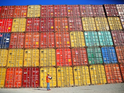 Un trabajador portuario examina contenedores en un muelle.