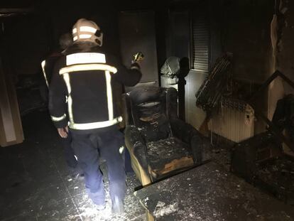 Los bomberos comprueban el interior de la vivienda incendiada.