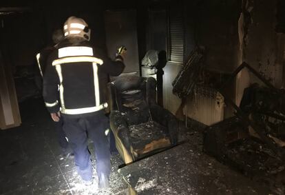 Los bomberos comprueban el interior de la vivienda incendiada.