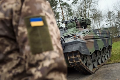 A Ukrainian soldier is standing in front of a Marder infantry fighting vehicle at the German forces Bundeswehr training area in Munster, Germany, Monday, Feb. 20, 2023.