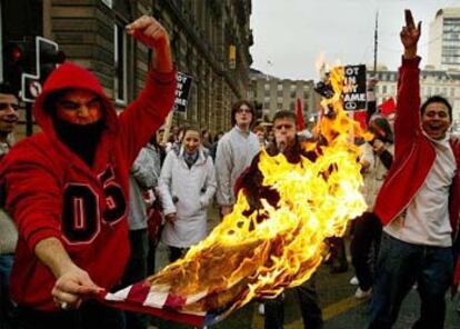 Unos jóvenes escoceses queman una bandera de los Estados Unidos en el centro de Glasgow. Las protestas llevadas a cabo en el Reino Unido arrojaron un saldo de, al menos, 36 personas detenidas por la policía.
