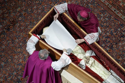 Los obispos Georg Gaenswein, a la derecha, y Diego Ravelli cubren el rostro del papa emérito Benedicto XVI con un velo de seda blanca en el interior de la basílica.