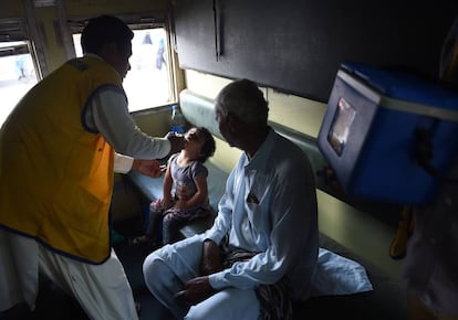 Un trabajador sanitario administra la vacuna de la polio a una niña en Karachi (Pakistán).