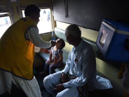 Un trabajador sanitario administra la vacuna de la polio a una niña en Karachi (Pakistán).