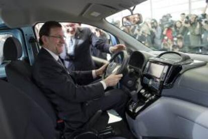 El presidente del Gobierno, Mariano Rajoy, acompañado por Patrick Danau, director general de Volkswagen Navarra, al volante de un modelo de esa marca durante su visita al Salón del Automóvil.