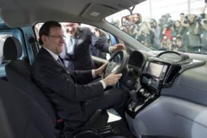 El presidente del Gobierno, Mariano Rajoy,  acompañado por  Patrick Danau, director general de  Volkswagen Navarra, al volante de un modelo de esa marca durante su visita al Salón del Automóvil.