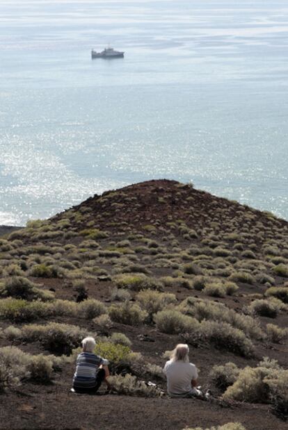 Dos turistas observan el buque Ramón Margalef en El Hierro.