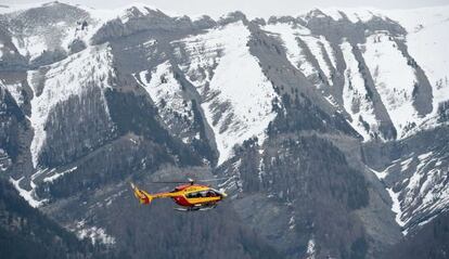 Un helicòpter sobrevola les muntanyes on hi ha l'avió accidentat.