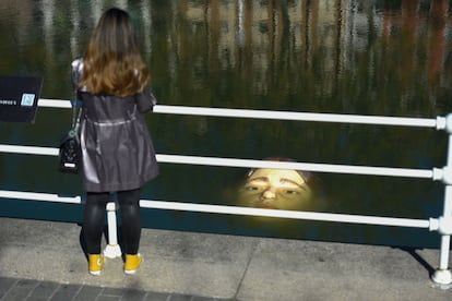 Una mujer observa la escultura Bihar (mañana, en euskera) del artista mexicano Rubén Orozco, sumergida en la ría de Bilbao.