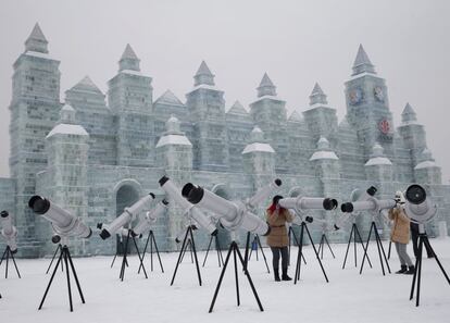 Unas espectadoras miran a través de unos caleidoscopios colocados junto a uno de los edificios de hielo, el 4 de enero de 2015.