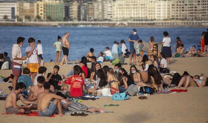 Grupos de bañistas, algunos de ellos sin mascarilla, en la playa de Ondarreta (Gipuzkoa). Residentes y bañistas de playas de distintos puntos de España critican junto al mar la medida publicada ayer en el Boletín Oficial del Estado (BOE), una ley que obliga a llevar la mascarilla puesta en cualquier espacio público, sin importar la distancia a la que se encuentre el resto de personas.