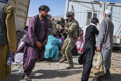 Un soldado estadounidense (en el centro) apunta con su arma hacia un afgano en el aeropuerto de Kabul, este lunes.