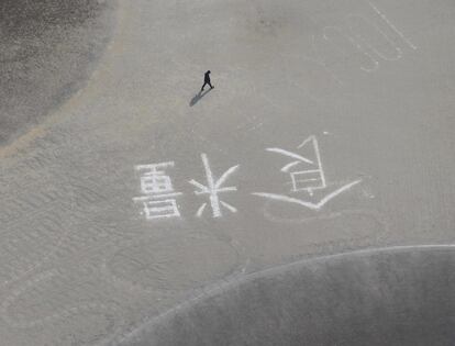 Un hombre camina por una playa donde alguien ha escrito la palabra "comida", en señal de auxilio ( Foto:THE YOMIURI SHIMBUM / MOTOKI NAKASHIMA (REUTERS)).
