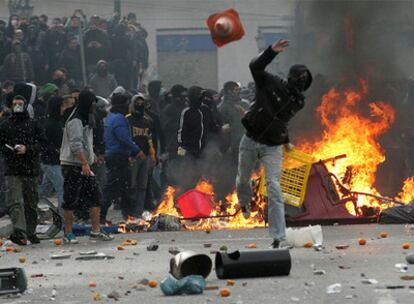 Un encapuchado lanza un objeto a la policía antidisturbios al término de una manifestación en el centro de Atenas.