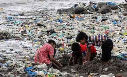 Varios niños juegan entre desechos de comida y plástico cerca de la costa del mar Arábigo, en la playa de Mahim, en Bombay (India)