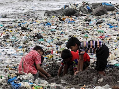 Varios niños juegan entre desechos de comida y plástico cerca de la costa del mar Arábigo, en la playa de Mahim, en Bombay (India)