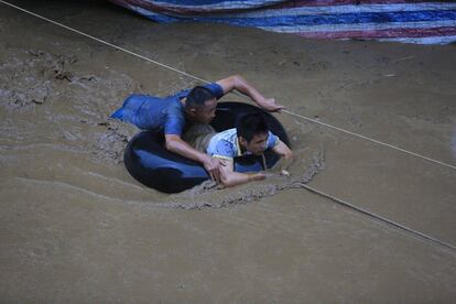 Dos personas son rescatadas con una cuerda y un flotador de una zona inundada en Liuzhou (China).